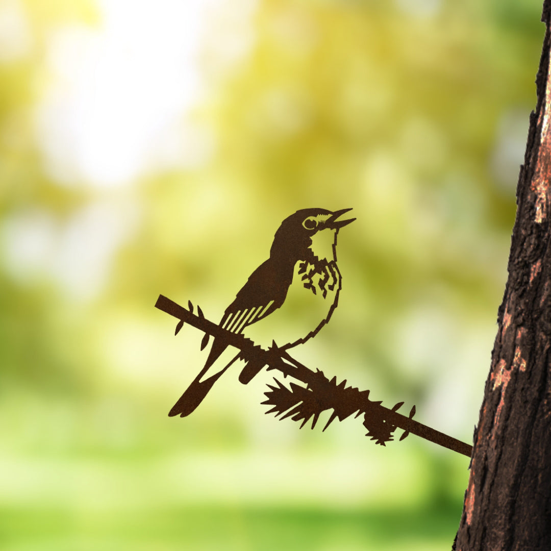 The Metalbird Canada silhouette of a Canada Warbler is perched on a branch, attached to a tree trunk, with a blurred green and yellow backdrop that evokes a sunny outdoor scene and celebrates bird conservation.