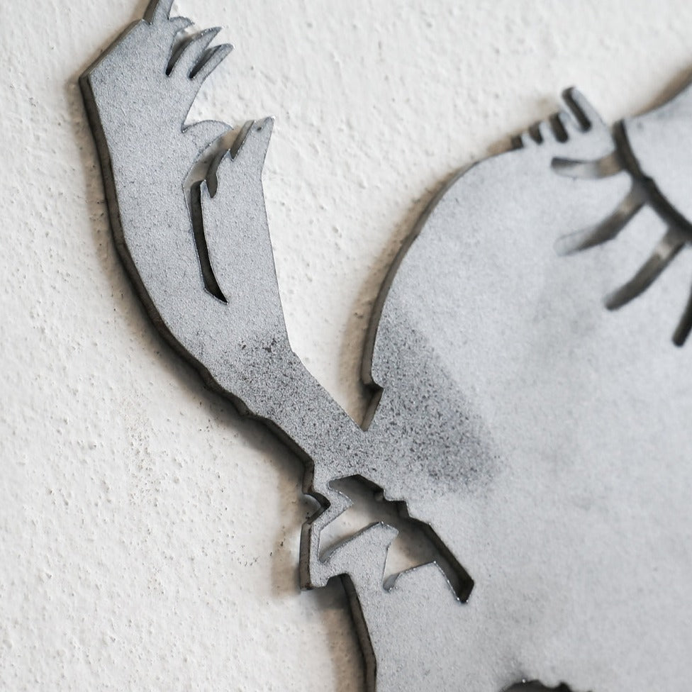 Close-up of the Metalbird Seconds by Metalbird Canada - Seconds, a gray corten steel silhouette featuring abstract, claw-like shapes and sharp lines against a textured white wall—an eye-catching piece of garden art.