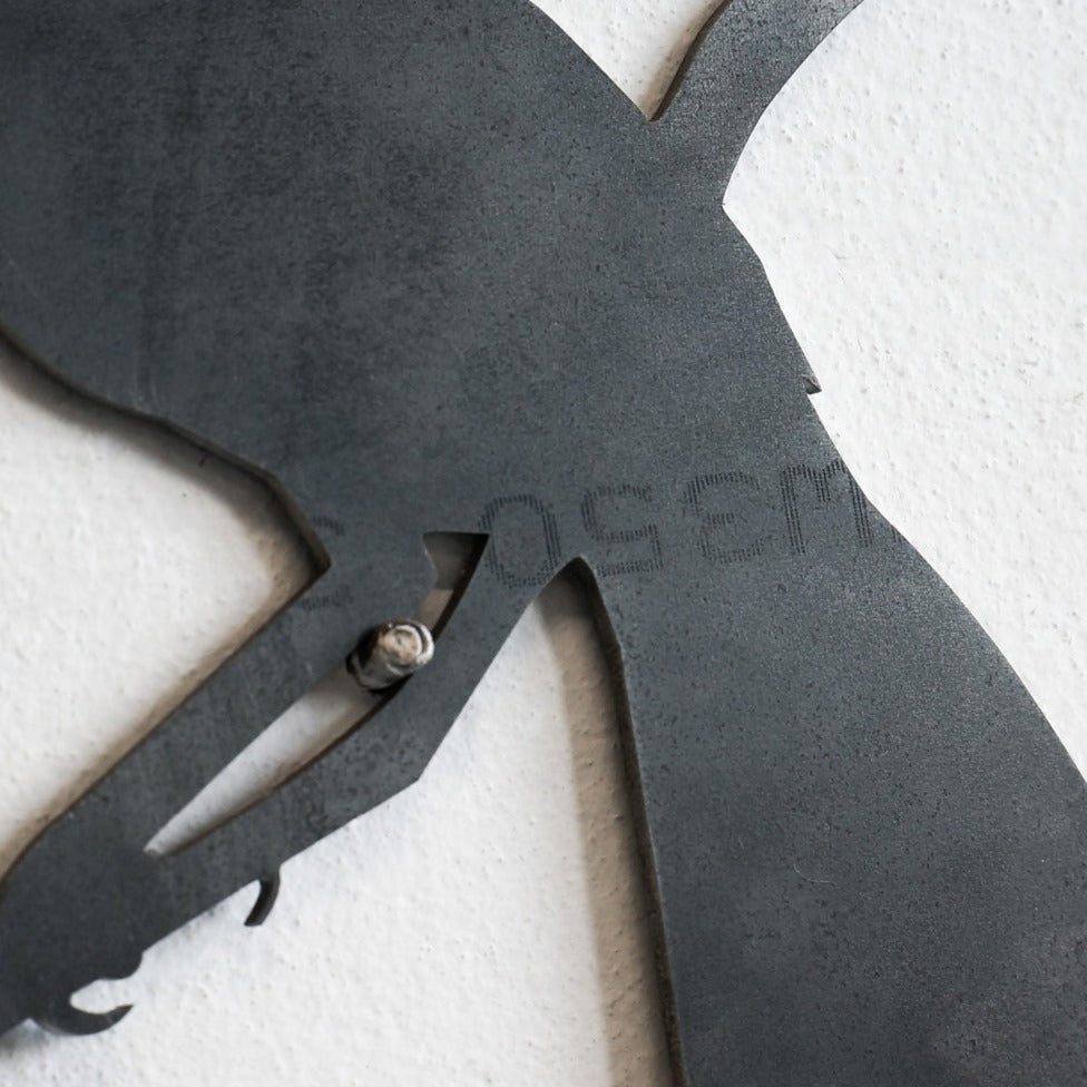 A close-up of the Metalbird Seconds by Metalbird Canada - Seconds, a matte black metal wall art featuring part of an animal silhouette and visible screws, ideal for adding unique indoor or garden decor.