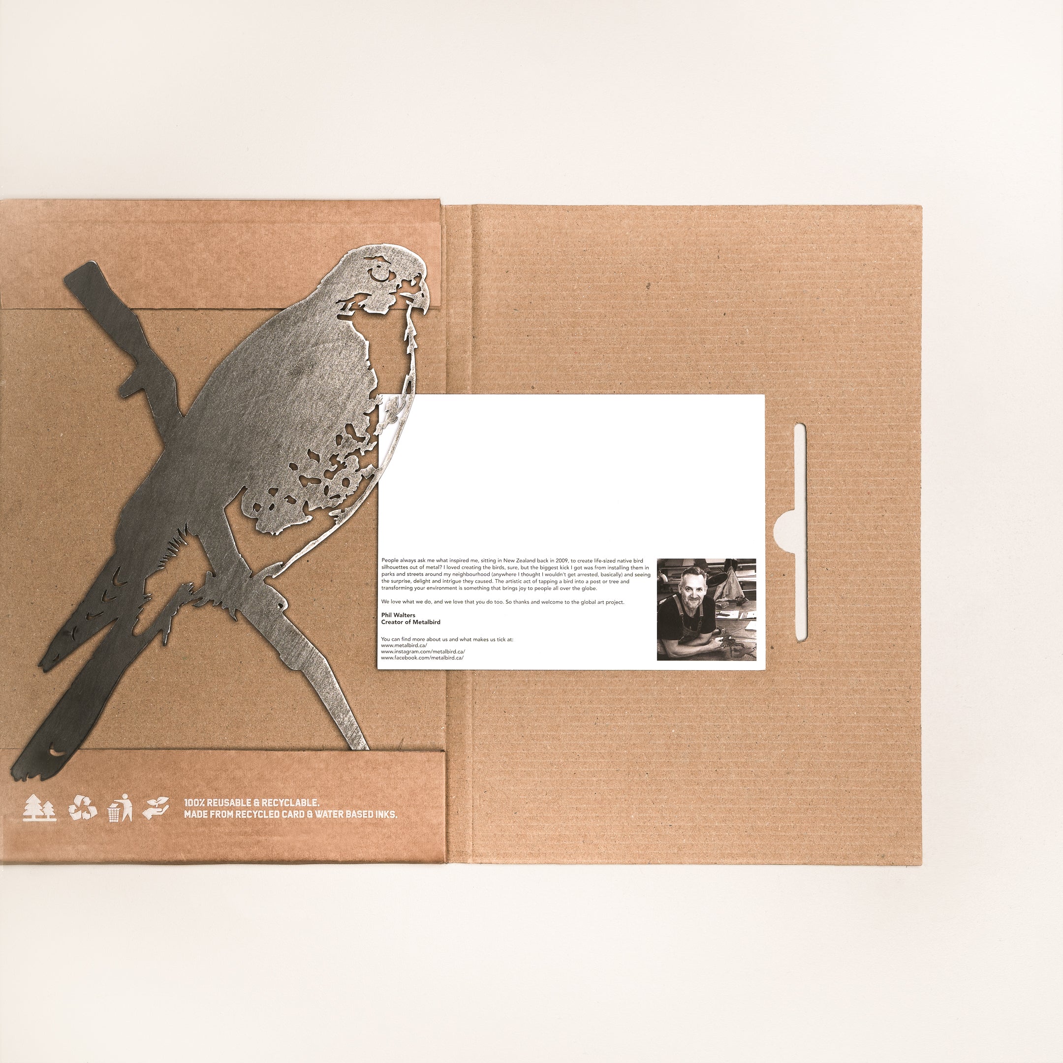 The Peregrine Falcon by Metalbird Canada features a cardboard folder with a metal falcon silhouette cutout on the left, partially covering a white card with black text and a small black-and-white photo on the right. Minimalist background, ideal for gifting.