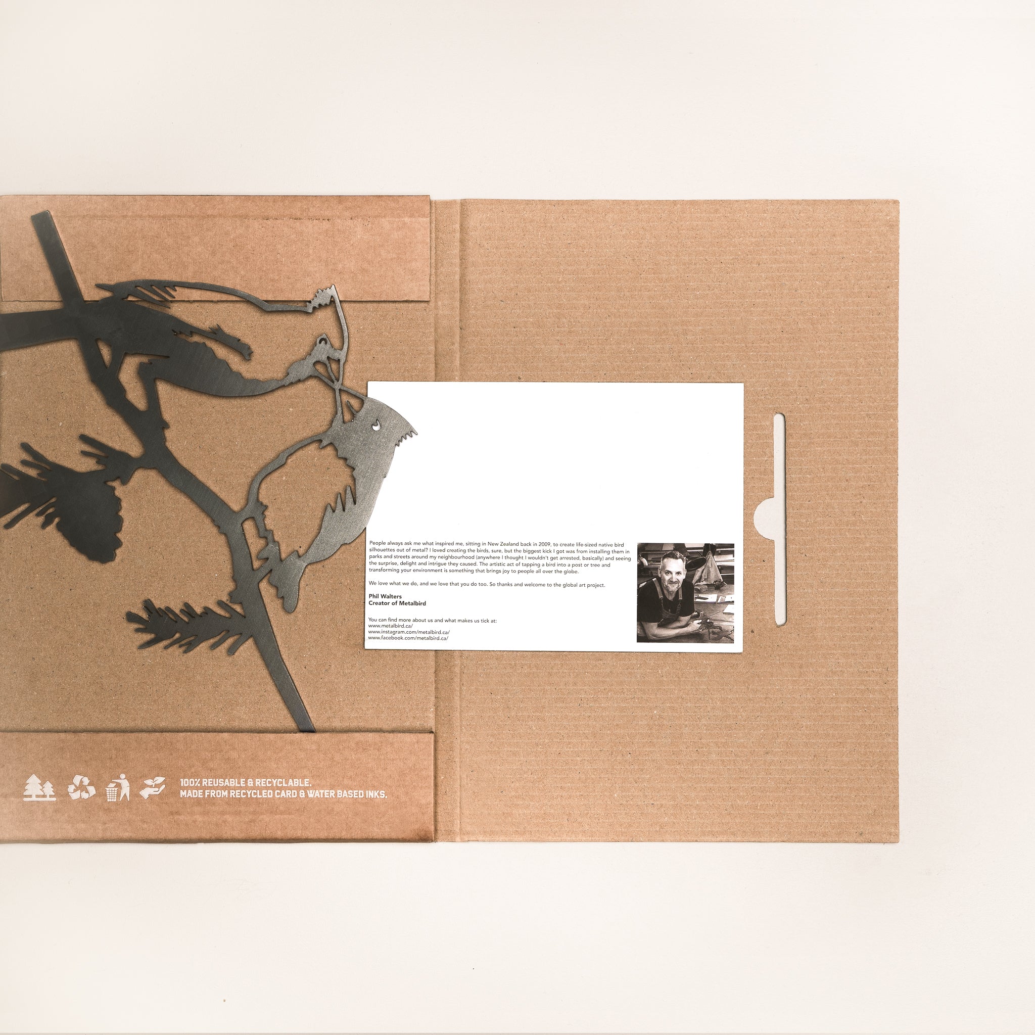 The Kissing Cardinals by Metalbird Canada is a brown, eco-friendly cardboard folder with bird cutouts, holding a white card with text and a small black-and-white photo, making it a unique gift against a plain white background.