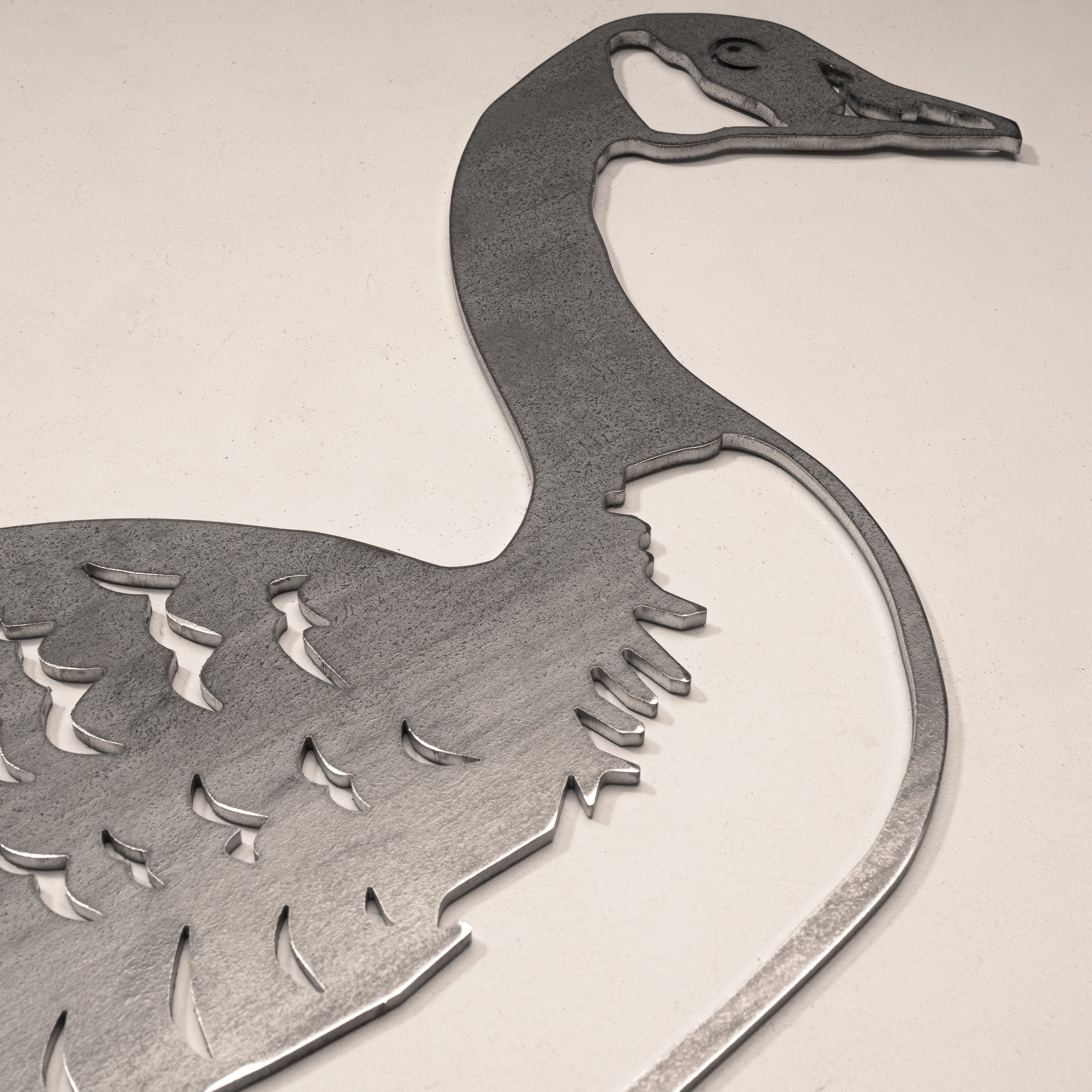 The Canada Goose metal wall art sculpture by Metalbird Canada features cutout feather details and rests on a light surface—ideal as unique yard art or a thoughtful gift.