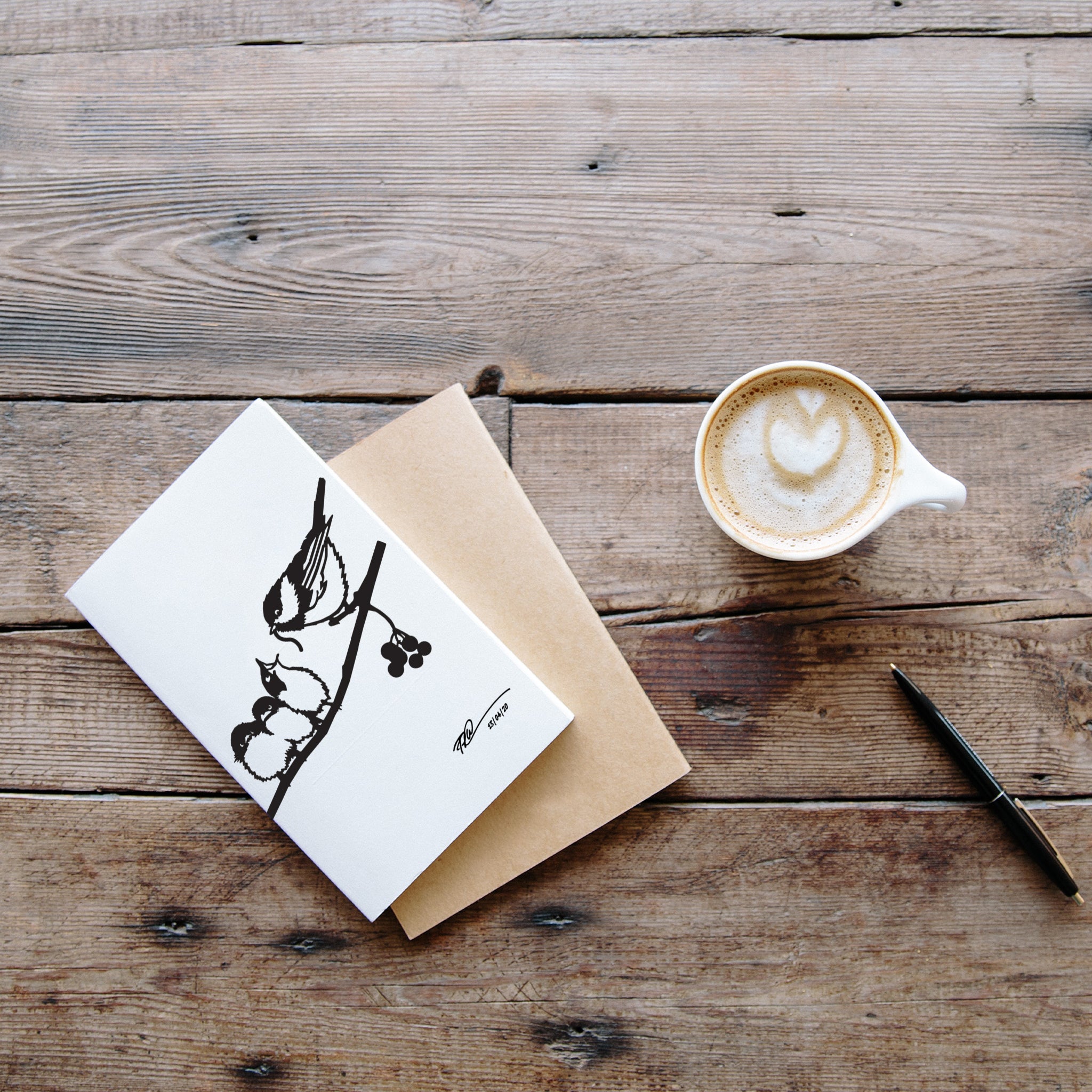 The Metalbird Greeting Card Set by Metalbird Canada, arranged alongside coffee and a pen on a rustic table, offers the perfect inspiration for unique bird garden art or makes an ideal, thoughtful gift.