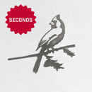 Metalbird Seconds by Metalbird Canada - Seconds features a bird silhouette perched on a branch, displayed against a white wall. A red starburst labeled SECONDS in the top left corner adds bold flair to this garden art-inspired decor.