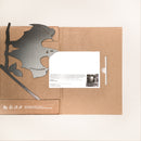 A brown cardboard folder from Metalbird Canada lies open with a black bat silhouette cutout on the left and a white paper with text and photo on the right. Icons and text are printed at the bottom left. Product name: Bat.