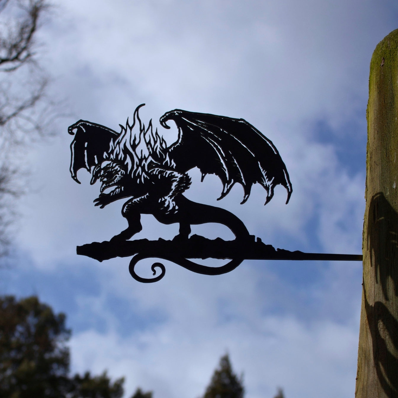 The BALROG™ by Metalbird Canada is a striking metal dragon silhouette with wings and flames, mounted on a post—an eye-catching piece of garden art for any outdoor setting.