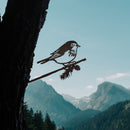 The Magnolia Warbler by Metalbird Canada is a corten steel bird silhouette perched on a branch, attached to a tree trunk for unique garden art.