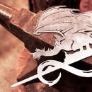 The FELL BEAST™ by Metalbird Canada is a corten steel dragon with a sword, set atop a rusty anvil in a workshop—ideal as unique yard art.