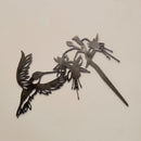 The Metalbird Canada Ruby-Throated Hummingbird is a handcrafted metal wall art sculpture featuring a hummingbird feeding from fuchsia flowers, designed with cutout details—perfect bird decor for bright, light-colored walls.