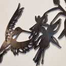 A close-up of the Ruby-Throated Hummingbird wall art by Metalbird Canada, featuring a black Corten steel design of a stylized hummingbird hovering near a flower on a plain light background.