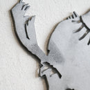 Close-up of the Metalbird Seconds by Metalbird Canada - Seconds, a gray corten steel silhouette featuring abstract, claw-like shapes and sharp lines against a textured white wall—an eye-catching piece of garden art.