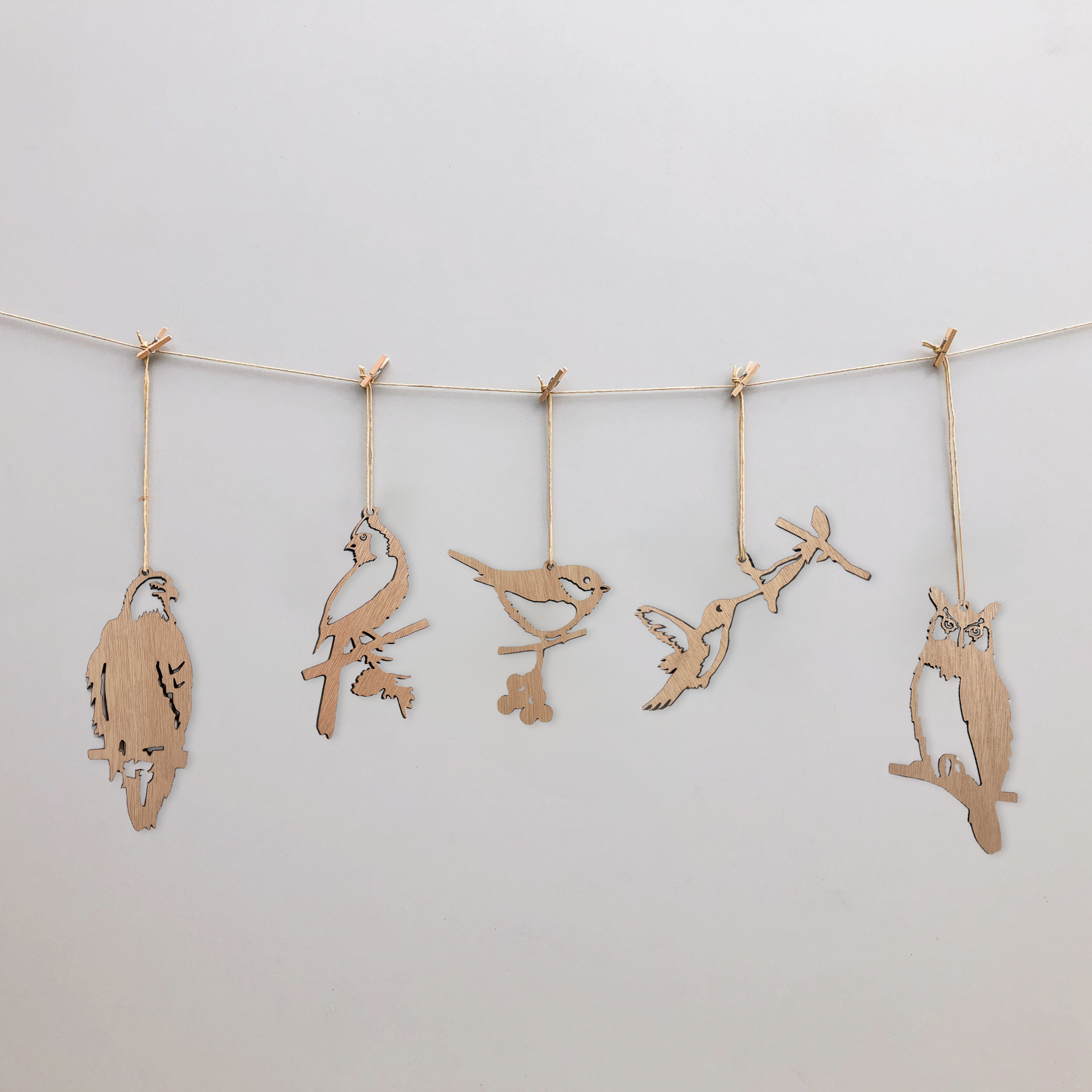 Metalbird Canada’s Wooden Hanging Decorations feature five unique bird silhouettes strung with clothespins, set against a white background. Ideal as minimalist yard art or a thoughtful gift, each bird is crafted in a delicate cut-out style.