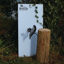 A Manumea bird silhouette by Metalbird Canada - CC perches on a wooden post beside a white BirdLife International sign, adorned with green ivy and set against lush foliage—blending yard art and nature perfectly.