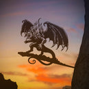 Create dramatic yard art with the BALROG™ metal silhouette from Metalbird Canada, featuring a winged demon mounted on a tree against a vibrant sunset of orange, yellow, and purple.