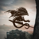 Mounted on a tree, the FELL BEAST™ metal silhouette by Metalbird Canada features outstretched wings, creating dramatic yard art against a backdrop of hills, water, and ancient ruins.
