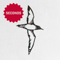 The Metalbird Seconds by Metalbird Canada - Seconds, featuring a bird in flight, is mounted on a white textured wall. A red starburst labeled "SECONDS" highlights its uniqueness, making it perfect for adding standout yard art to your space.