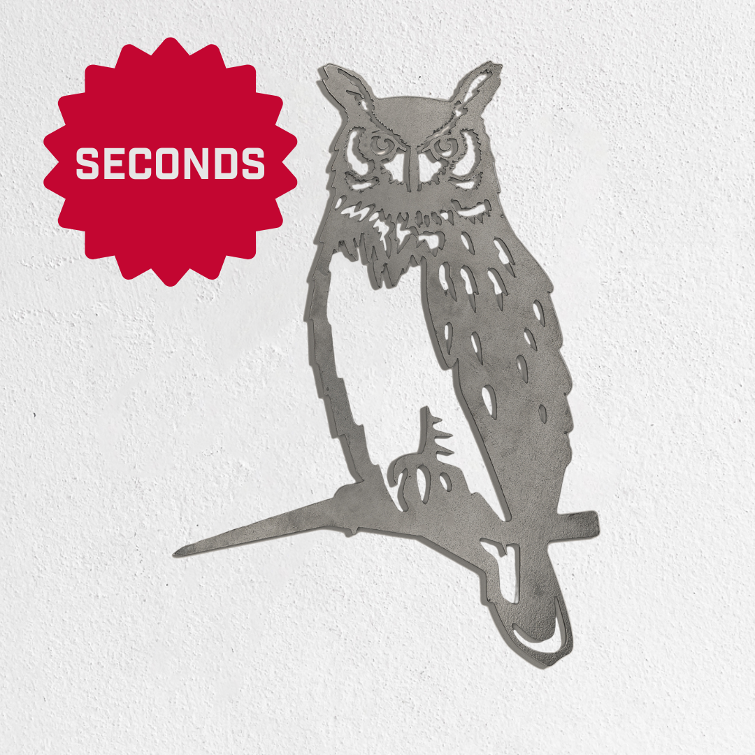 A Metalbird Seconds owl silhouette by Metalbird Canada - Seconds, perched on a branch, is mounted on a white wall. A red starburst with "SECONDS" in white appears in the top left—distinctive garden art.