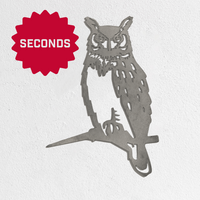 A Metalbird Seconds owl silhouette by Metalbird Canada - Seconds, perched on a branch, is mounted on a white wall. A red starburst with "SECONDS" in white appears in the top left—distinctive garden art.