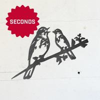 Metalbird Seconds by Metalbird Canada - Seconds: two birds perched on a branch, crafted from corten steel and mounted on a white wall. A red starburst with "SECONDS" in white appears in the top left corner.