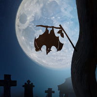 The Bat by Metalbird Canada features a corten steel silhouette of a bat hanging from a branch, set against gravestones and a full moon—ideal as spooky garden art.