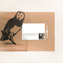 A unique gift, the Barn Owl by Metalbird Canada is a cardboard folder with a barn owl cutout perched on a branch, reminiscent of yard art, and includes a white card with text plus a black-and-white photo of a man inside.