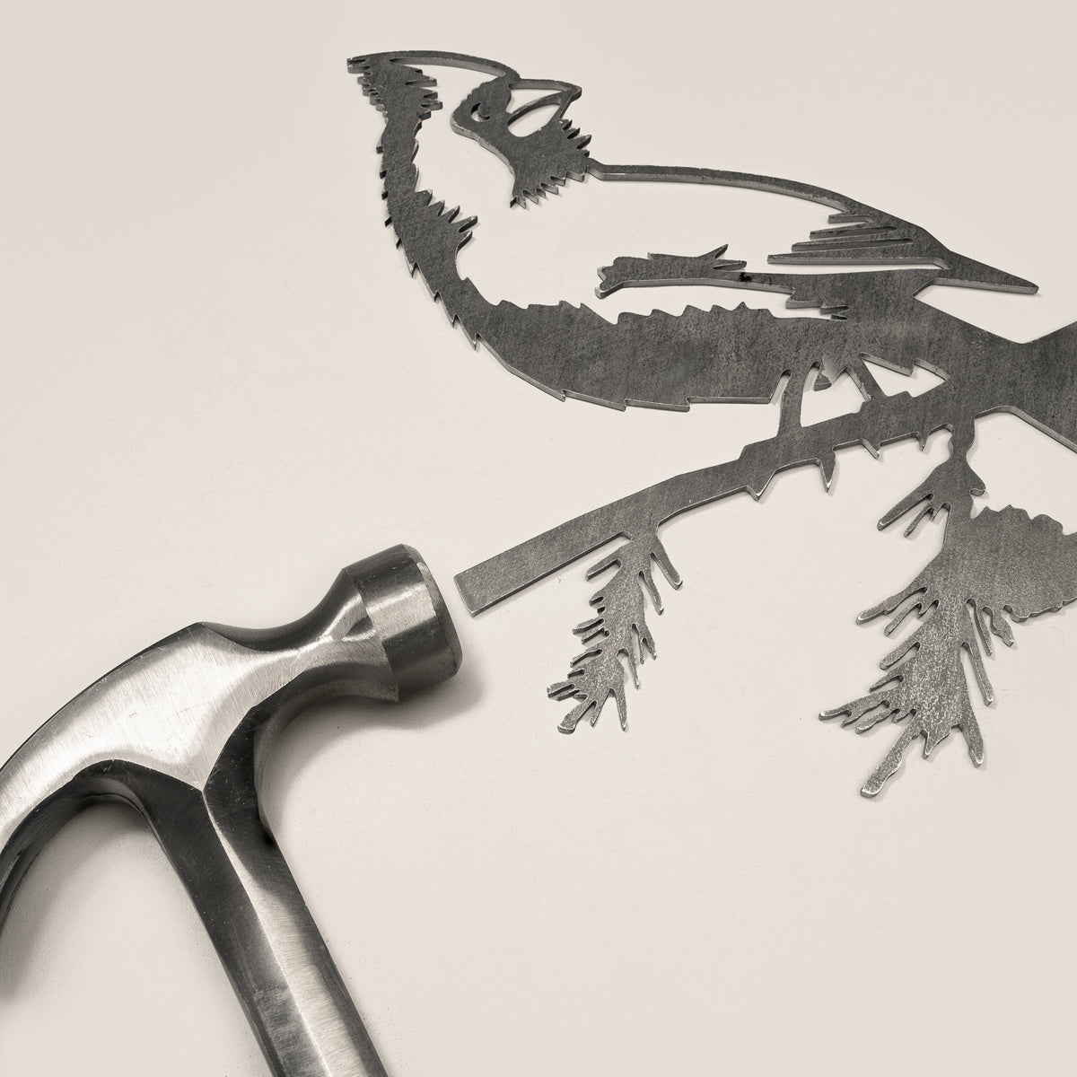 Cardinal steel silhouette and integrated mounting spike beside a claw hammer.