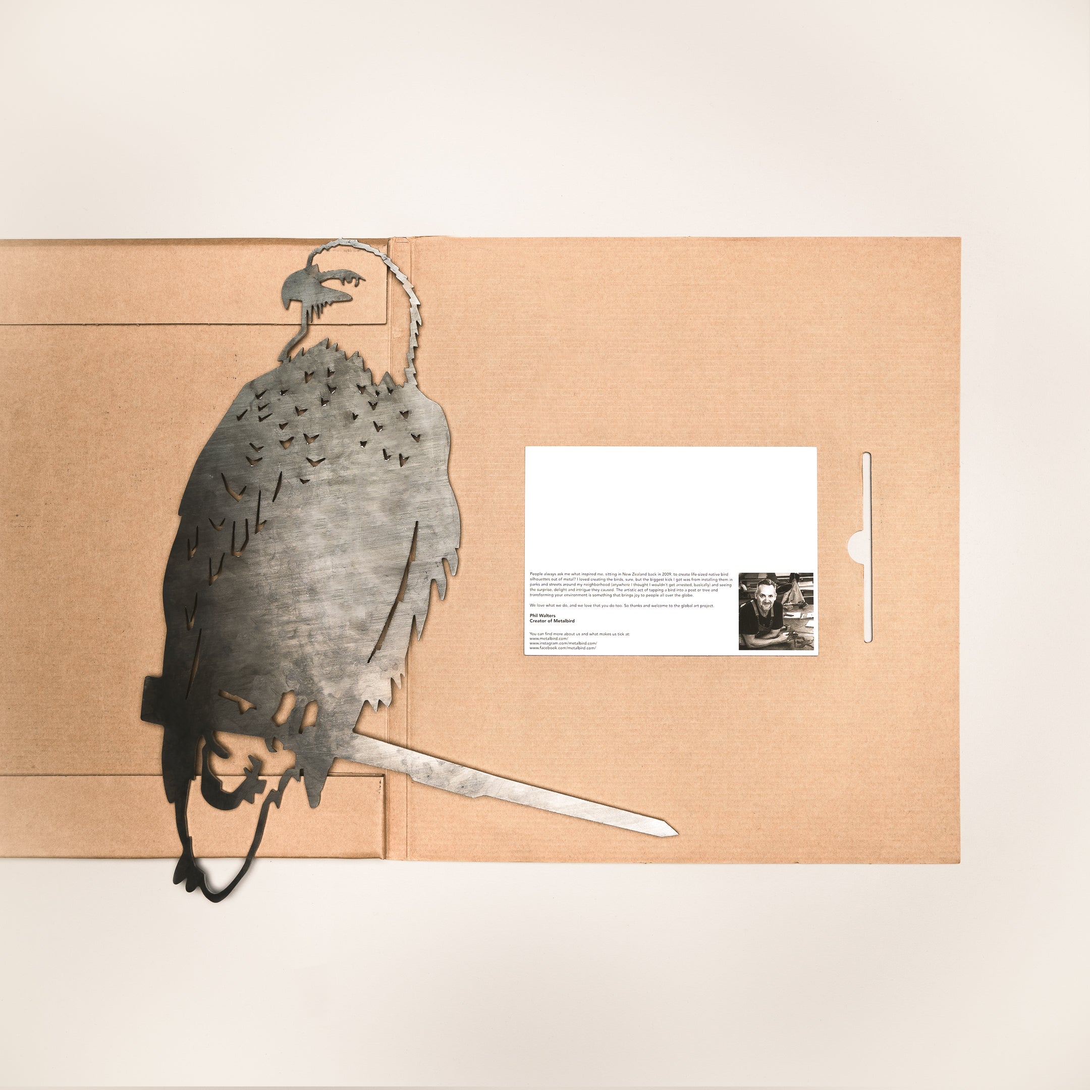 A brown folder from Metalbird Canada lies open on a white surface, featuring a Bald Eagle silhouette cutout on the left and a white card with text and small images on the right—perfect for garden art lovers or as a unique gift.