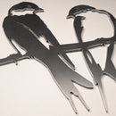 The Pair of Swallows by Metalbird Canada features two stylized birds perched on a branch. Made from corten steel, this metal garden art showcases sharp edges and minimal detailing for a modern outdoor display.