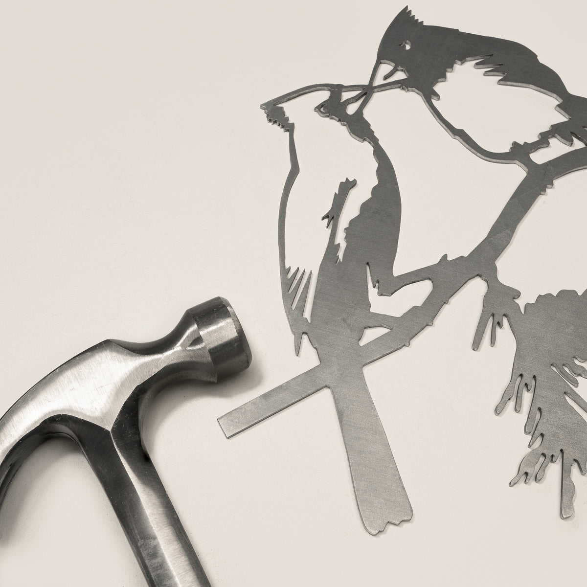 Kissing Cardinals steel silhouette and integrated mounting spike beside a claw hammer.