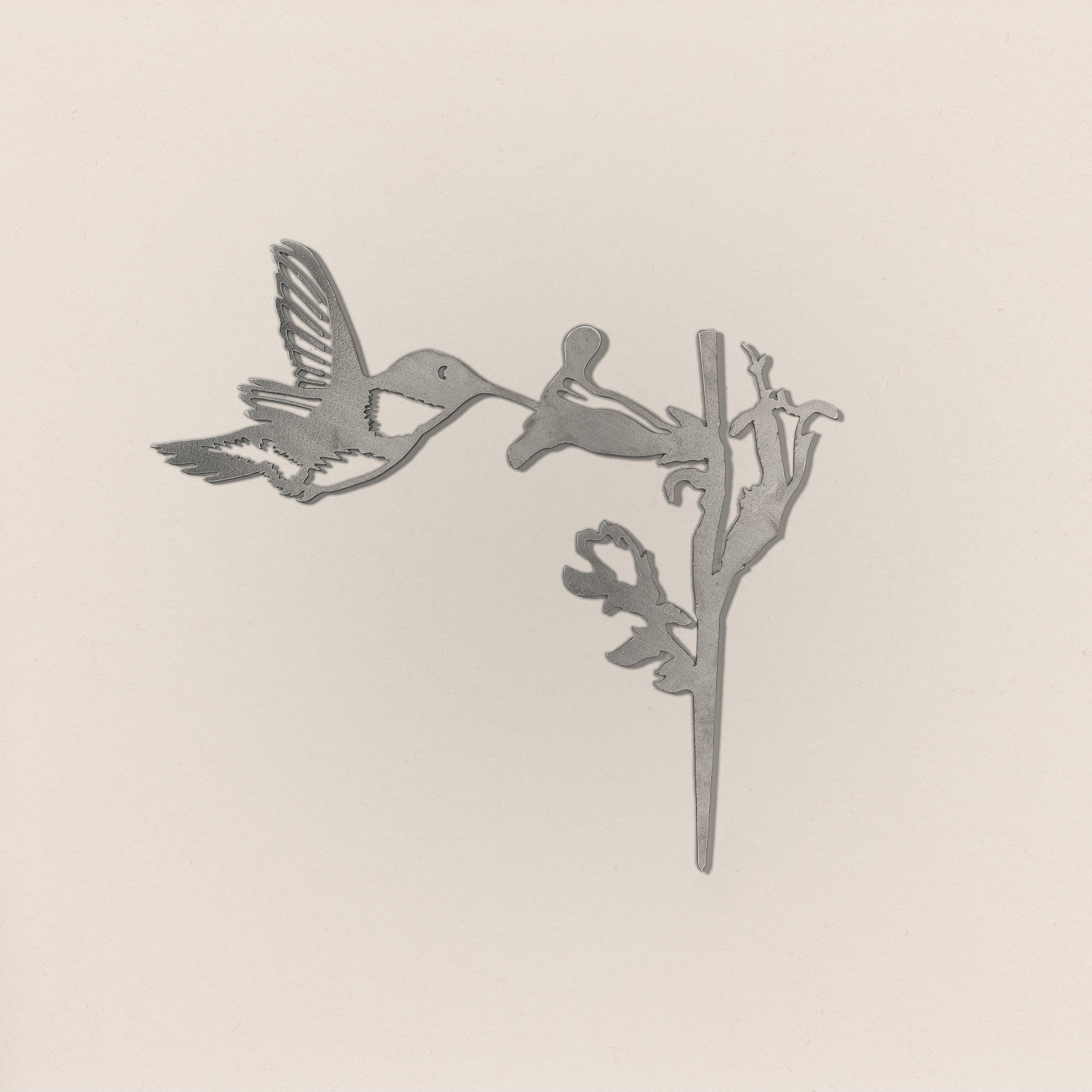 The Hummingbird by Metalbird Canada features a minimalist, monochrome design of a hummingbird feeding from a trumpet-shaped flower—ideal as metal yard art or a thoughtful gift.