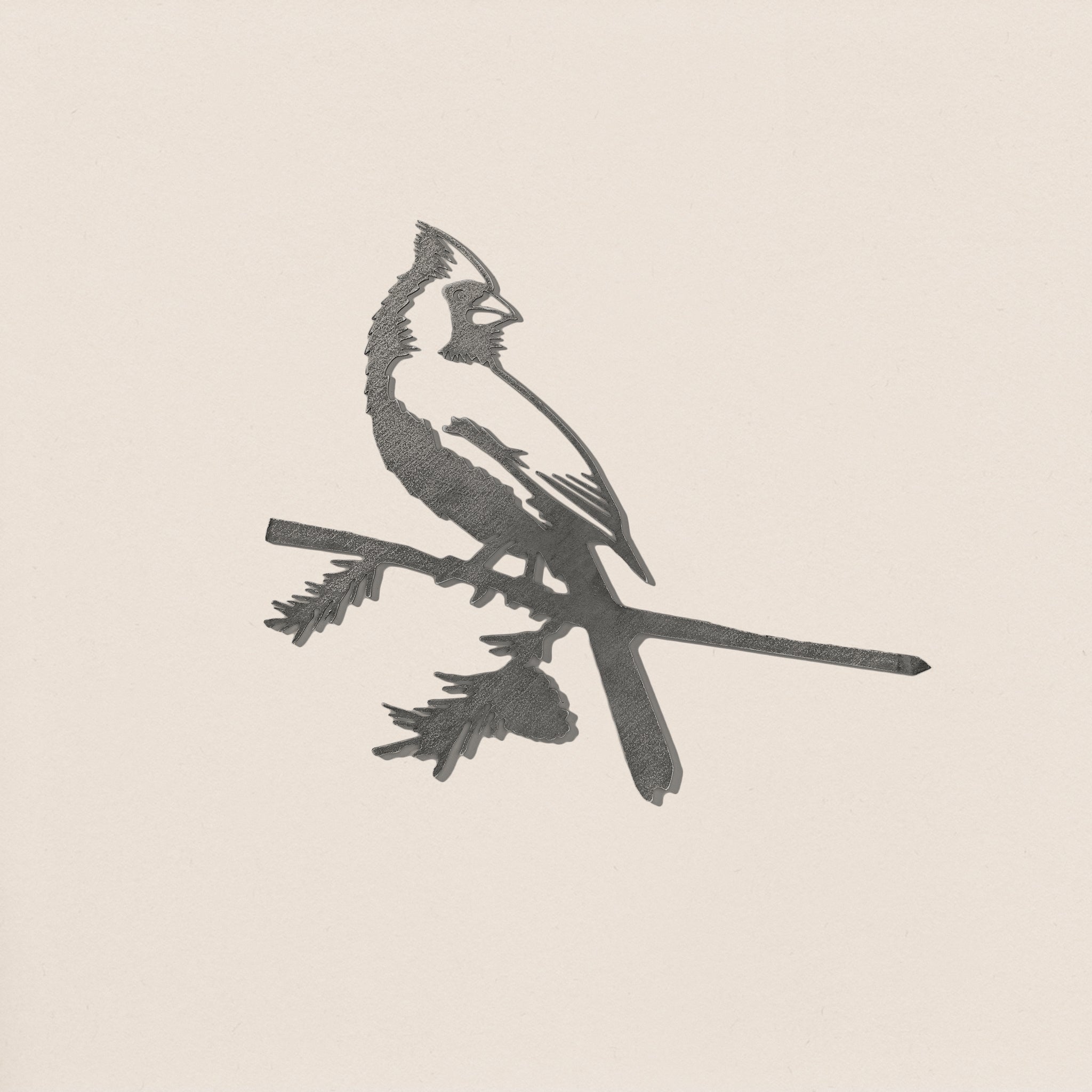 The Cardinal by Metalbird Canada features a sleek black and white silhouette with its crest, perched on a leafy branch against a light background—ideal as a unique gift or standout piece of yard art.