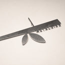 The Stick Bird Feeder by Metalbird Canada features a ruler-shaped metallic design with keys and leaf-like accents, making it unique garden art or a thoughtful gift, shown here on a light-colored surface.