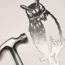 The Great Horned Owl by Metalbird Canada is a detailed metal cutout with lifelike feathers and facial features, shown next to a silver hammer on a light surface—a unique garden art gift for nature lovers.