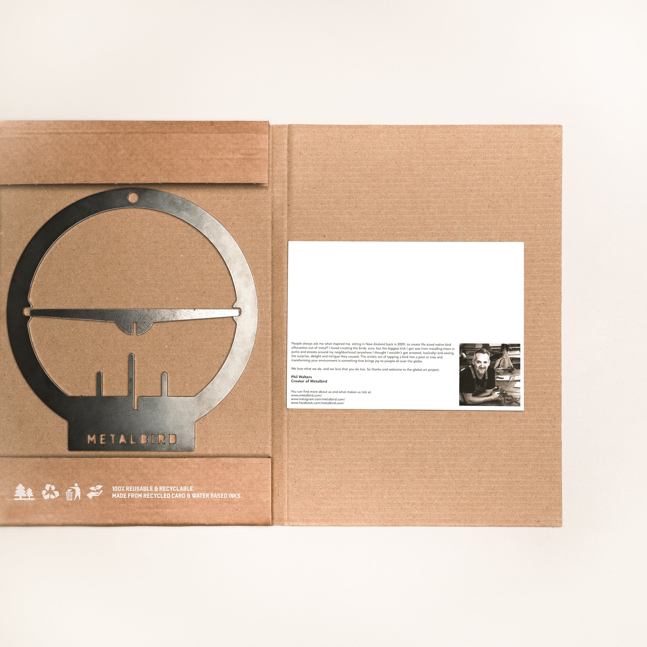 On the left, a Hanging Bird Feeder by Metalbird Canada sits in its packaging. On the right is a brown folder with a card featuring a black-and-white photo and message—perfect garden art for any space.