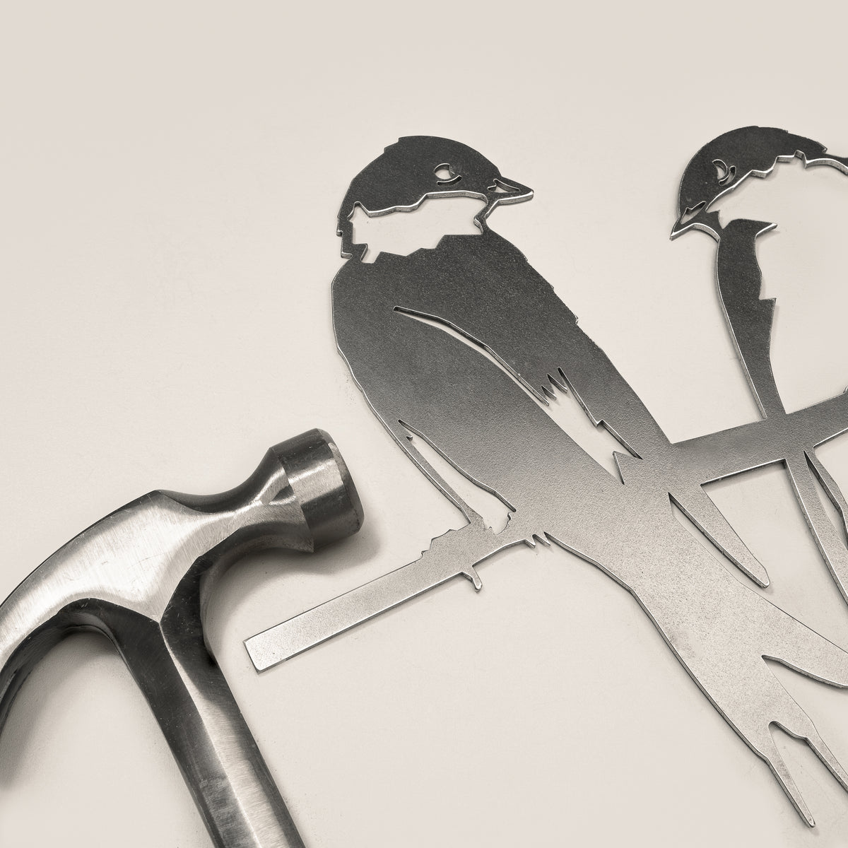 Pair of Swallows steel silhouette and integrated mounting spike beside a claw hammer.