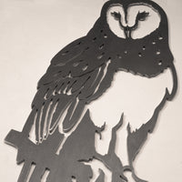 The Barn Owl by Metalbird Canada is a metal wall art piece with a cut-out silhouette of an owl perched on a branch, showcasing feather and facial details against a light-colored wall.