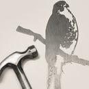 A silver hammer beside Metalbird Canada’s “Peregrine Falcon” corten steel silhouette, both set on a light surface—an ideal gift for nature lovers.