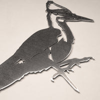 Metalbird Canada’s Pileated Woodpecker is a corten steel silhouette art piece showing a stylized woodpecker on a branch, ideal as unique garden art against a light background.
