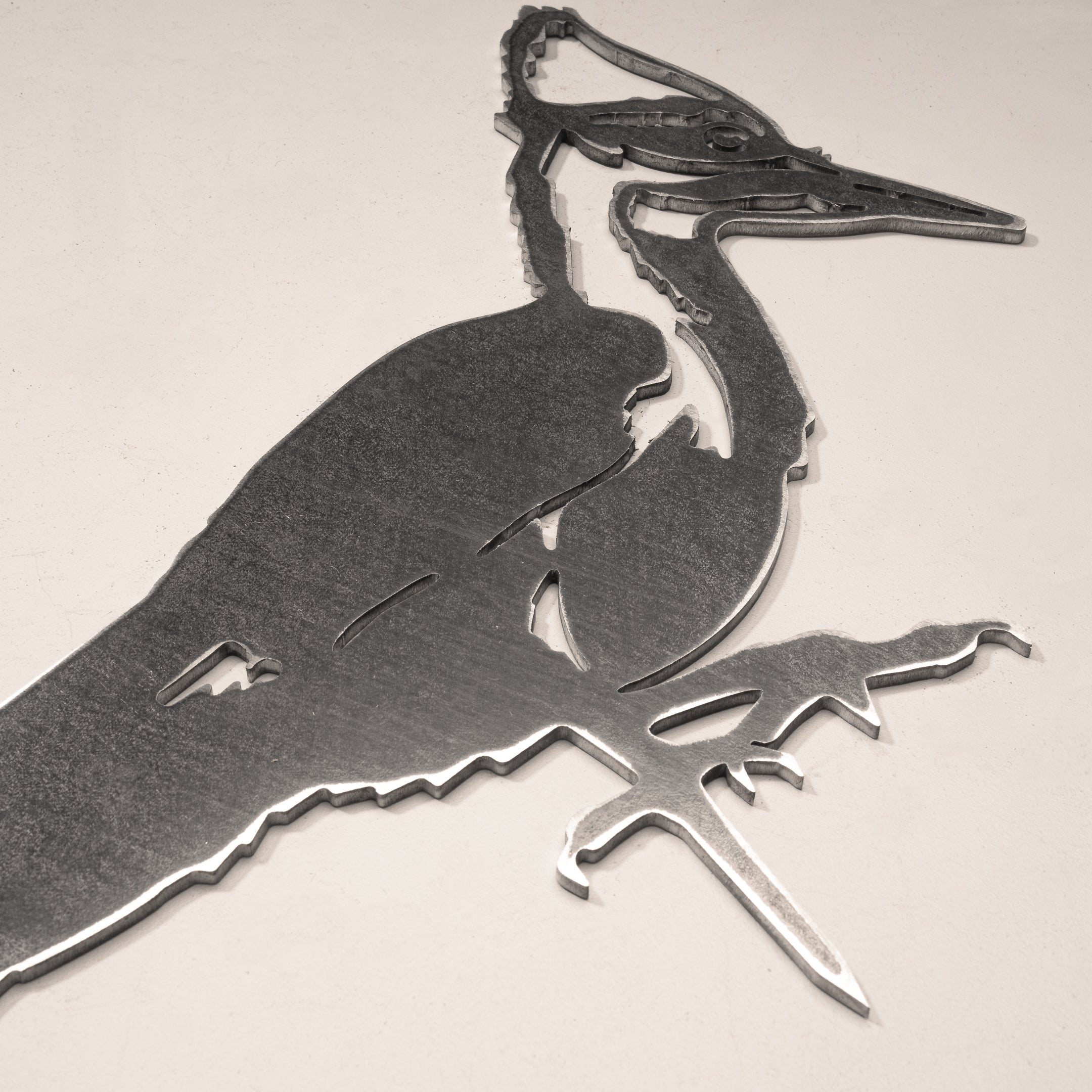 Metalbird Canada’s Pileated Woodpecker is a corten steel silhouette art piece showing a stylized woodpecker on a branch, ideal as unique garden art against a light background.