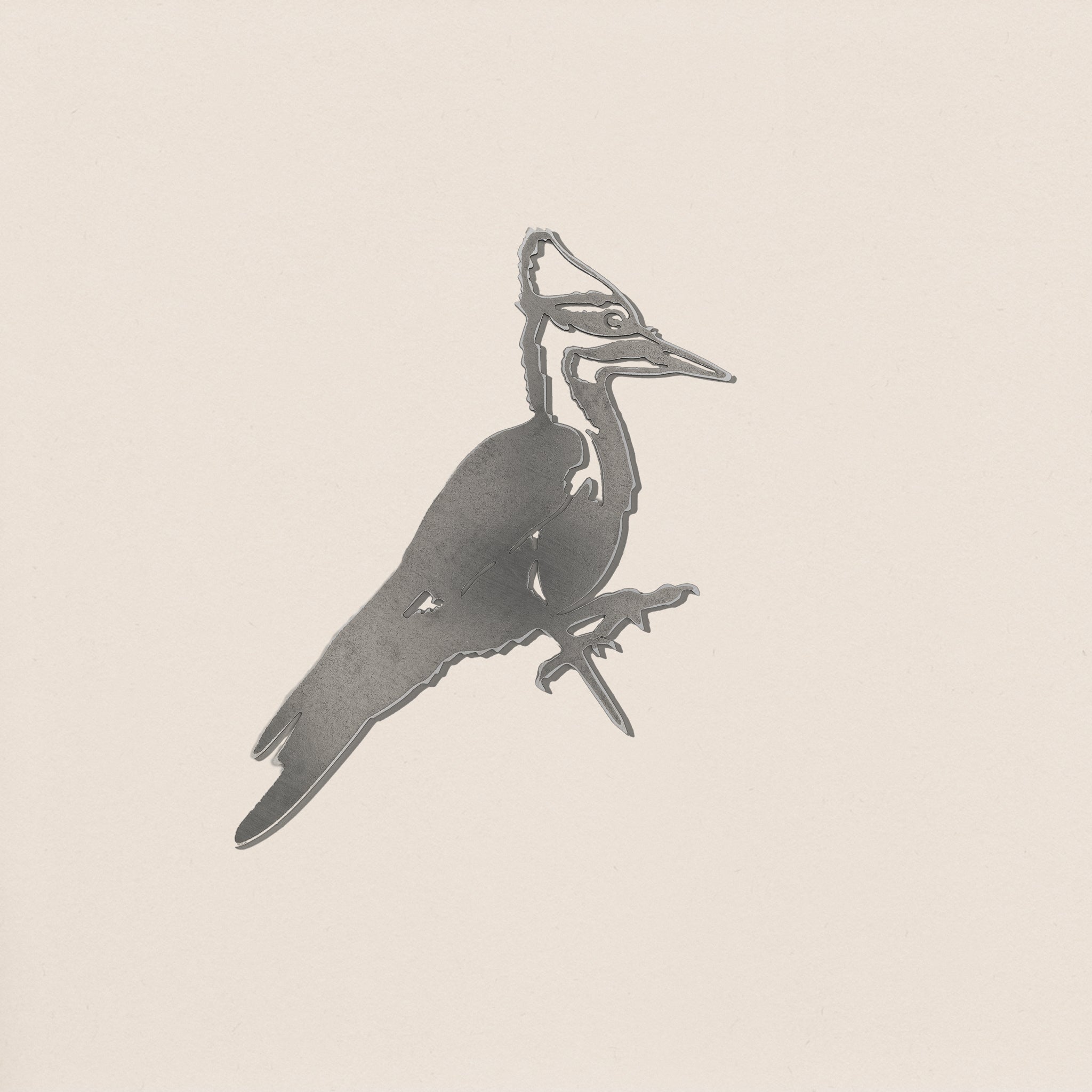 The Pileated Woodpecker by Metalbird Canada features a grayscale, minimalist design highlighting the bird’s crest and long beak—ideal inspiration for corten steel yard art against a simple light background.