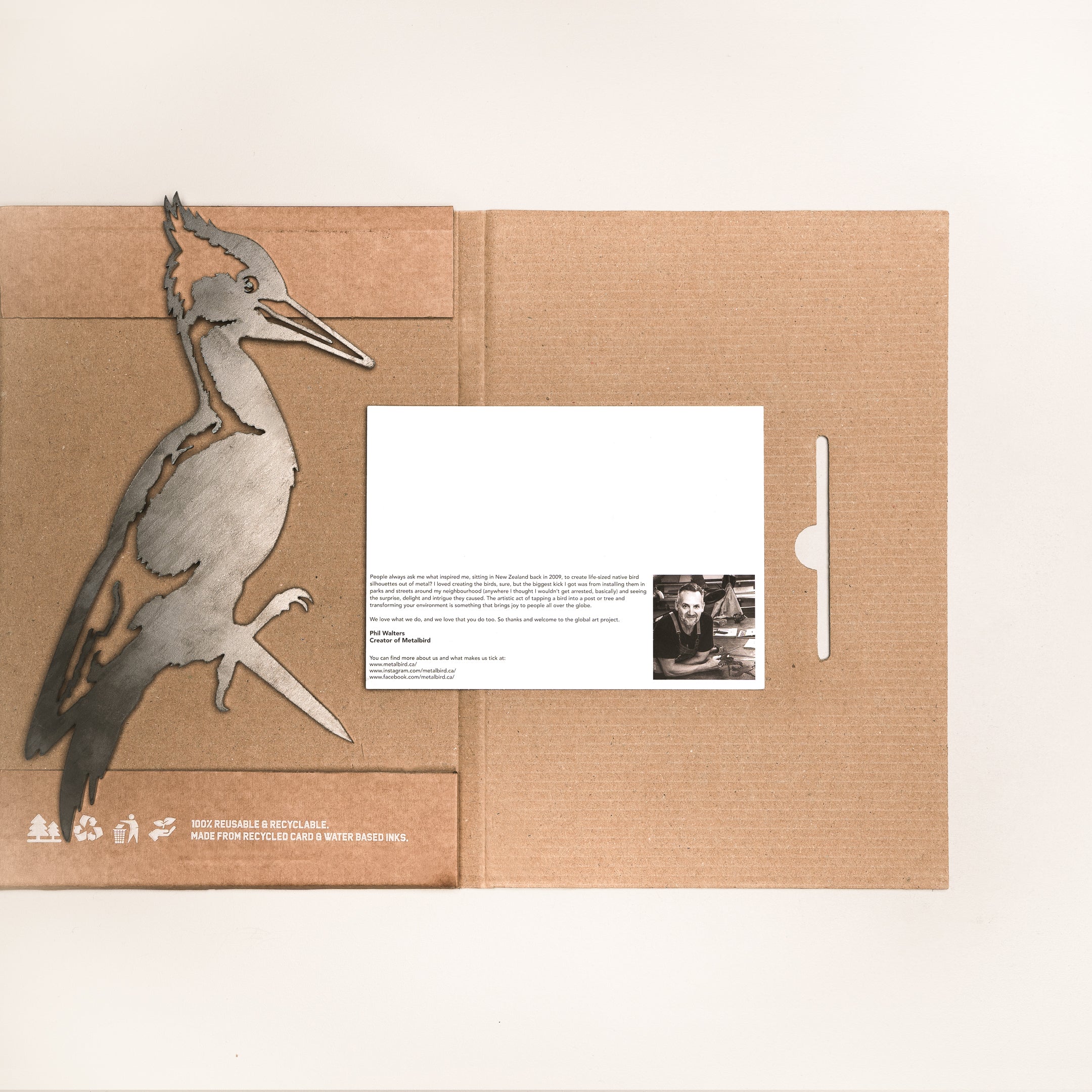 A unique gift: the Pileated Woodpecker folder by Metalbird Canada, made from recycled cardboard with a metal bird cutout. Includes a postcard featuring a black-and-white photo and text—perfect for garden art lovers.