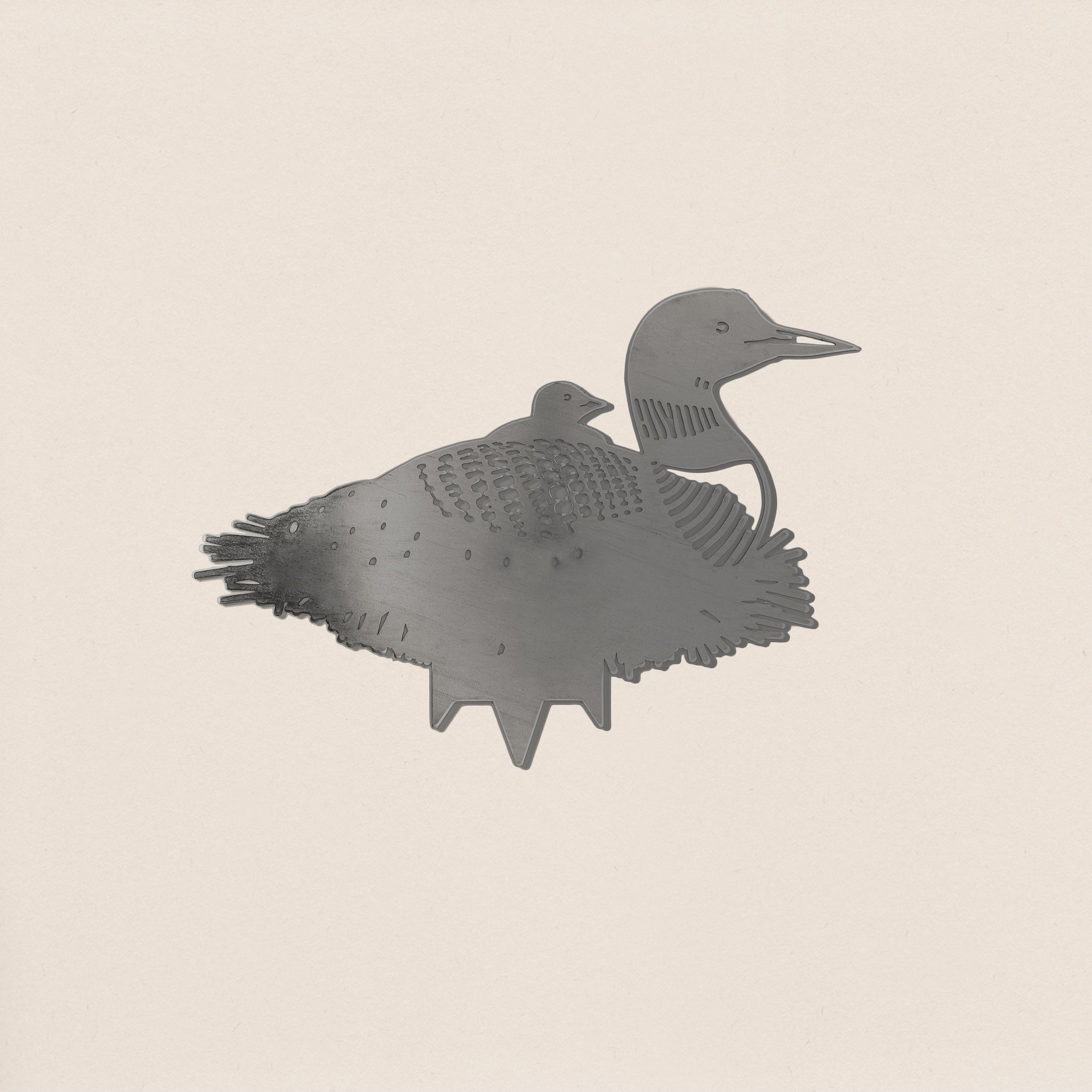The Common Loon by Metalbird Canada is a corten steel cutout showing a loon with a chick on its back. With etched feather and face details, it’s perfect as unique garden art, displayed on a light background.