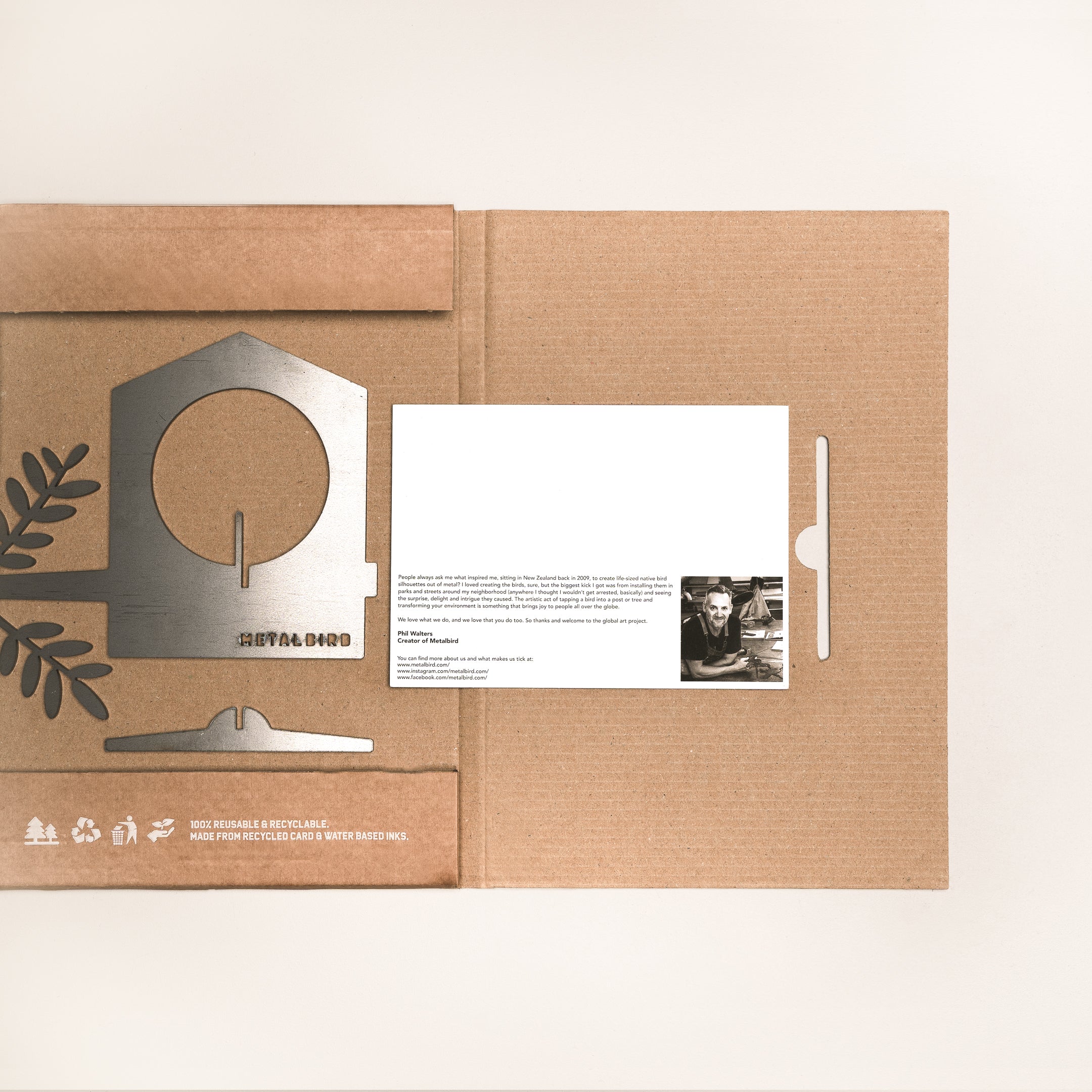 A flat cardboard box displays the Metalbird Canada Bird Feeder kit and a card with text and a photo. Leaf designs and recycling symbols on the box make it perfect for garden art fans.