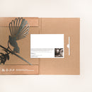 The Fantail / New Zealand Pīwakawaka by Metalbird Canada features a brown cardboard folder with a black corten steel bird silhouette on the left and a white card with text and photo on the right—an ideal unique gift.