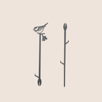 The Chickadee Plant Stake - 25" by Metalbird Canada features a striking black metal silhouette of a bird with berries, adding distinctive garden art to any space. Displayed on a plain, light background, it's the perfect accent for your outdoor decor.