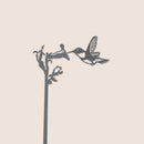 The Hummingbird Plant Stake - 25" by Metalbird Canada features a sleek black corten steel silhouette of a hummingbird drinking from a long-stem flower—an elegant gift for any nature lover.