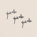 The Baby Bird Bundle - Hummingbird Trio by Metalbird Canada features three hummingbird silhouettes perched on branches in a diagonal arrangement, each casting a unique shadow on a light beige background.
