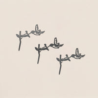The Baby Bird Bundle - Hummingbird Trio by Metalbird Canada features three hummingbird silhouettes perched on branches in a diagonal arrangement, each casting a unique shadow on a light beige background.